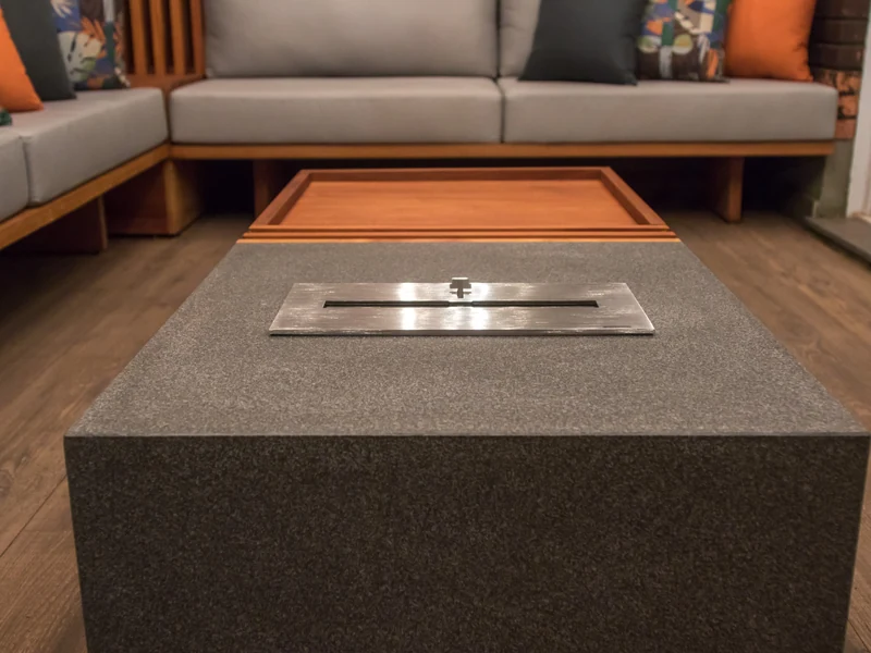 Detalhe do queimador QS-1500 QS-1500-A da Somer embutido em bancada de granito sobre estrutura de madeira, com tampa guilhotina aberta sobre lounge contemporâneo, projeto Luma Trevisan, foto Ricardo Fabrello