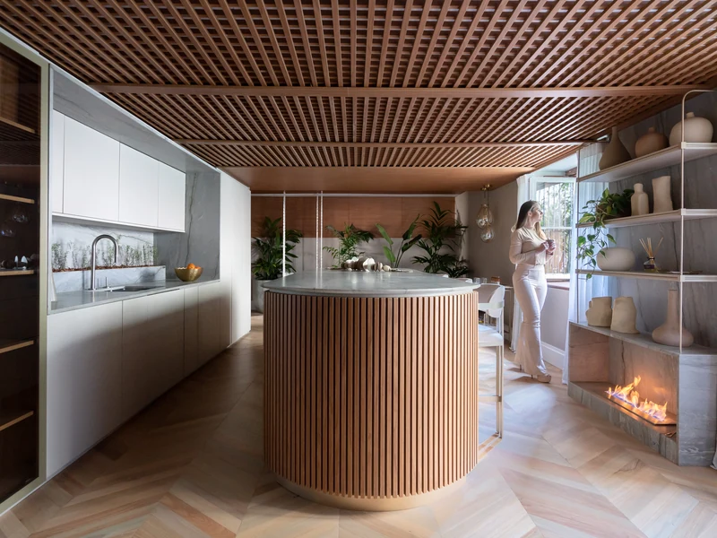 Detalhe do queimador QS-3000 QS-3000-A da Somer com chama acesa embutido em painel de pedra natural em cozinha contemporânea com teto ripado iluminado e ilha em ripado de madeira, projeto CB Melina Knopp