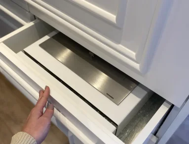 Compartimento do queimador da Lareira GO! Branca LSG-1500-B sendo aberto em móvel com pintura eletrostática branco fosco, mostrando o queimador em aço inox 304